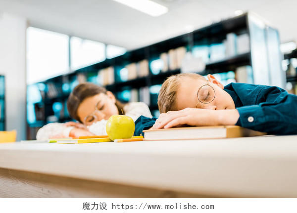 疲惫的学童睡在图书馆的桌子上学习压力困扰
